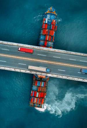 bateau cargo sous un pont sur lequel roulent des véhicules
